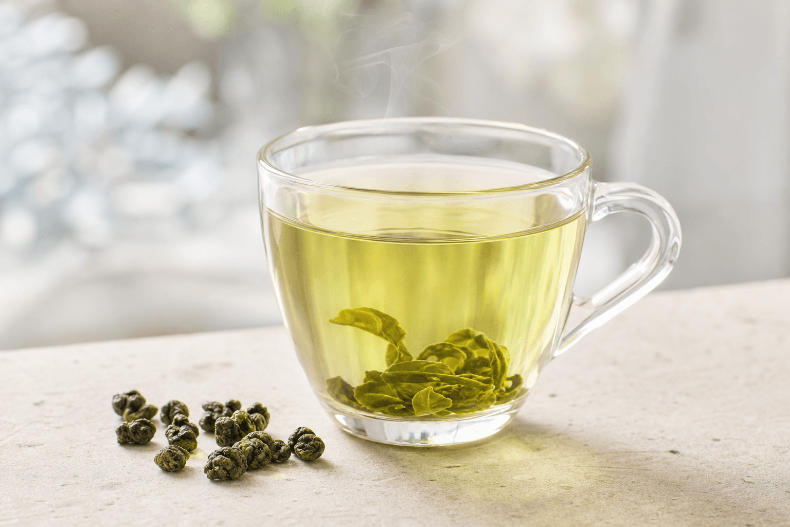 A clear glass cup of bright yellow-green Tie Guan Yin oolong on a pale stone surface
