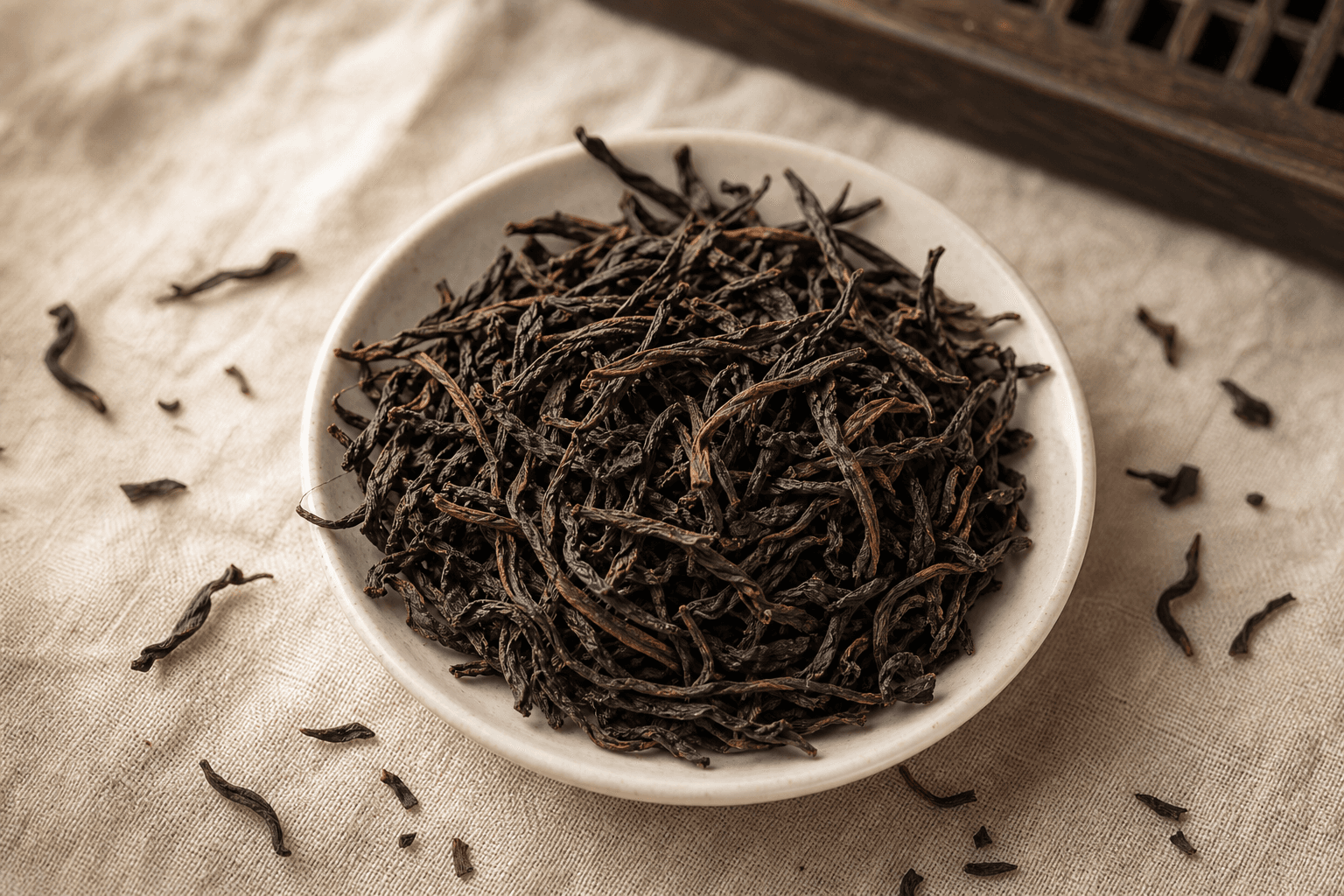 Long, dark, twisted Mi Lan Xiang Dancong oolong leaves on a cream linen surface, showing a faint reddish-brown sheen