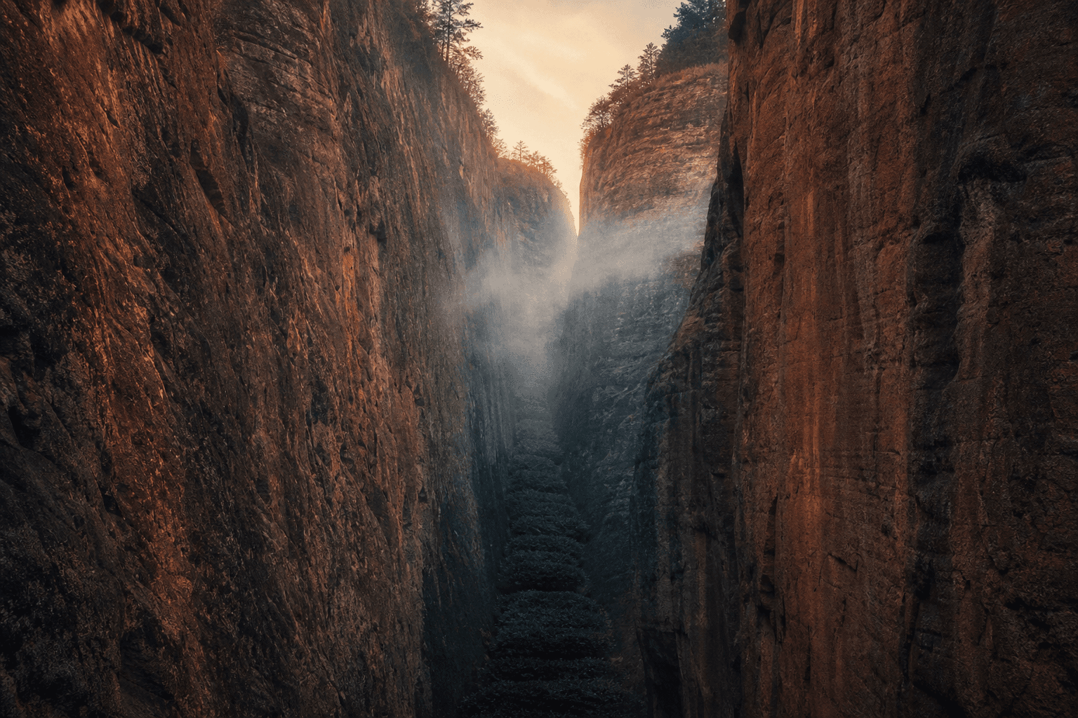 Steep vertical sandstone cliffs of the Wuyi Mountains with tea bushes growing in a narrow ravine between vertical rock walls in morning mist